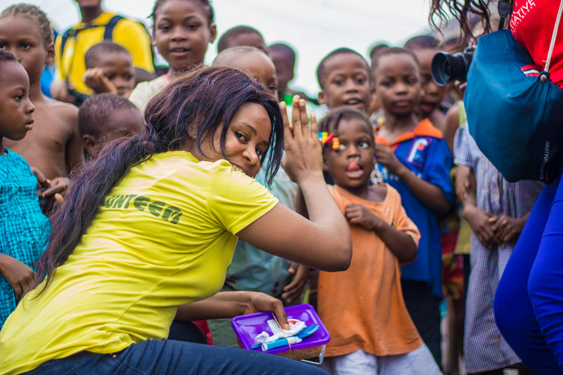 A vibrant scene of children and volunteers participating in an outdoor community outreach activity.