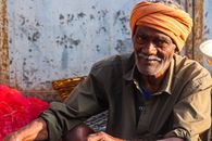 Man in Brown Thobe Sitting on Red Textile