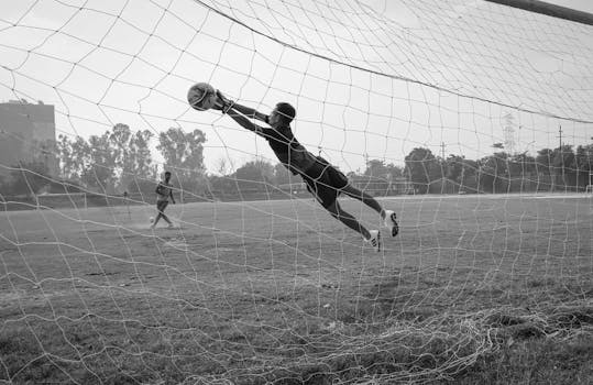 A goalkeeper makes an impressive dive to save a soccer ball during a match.