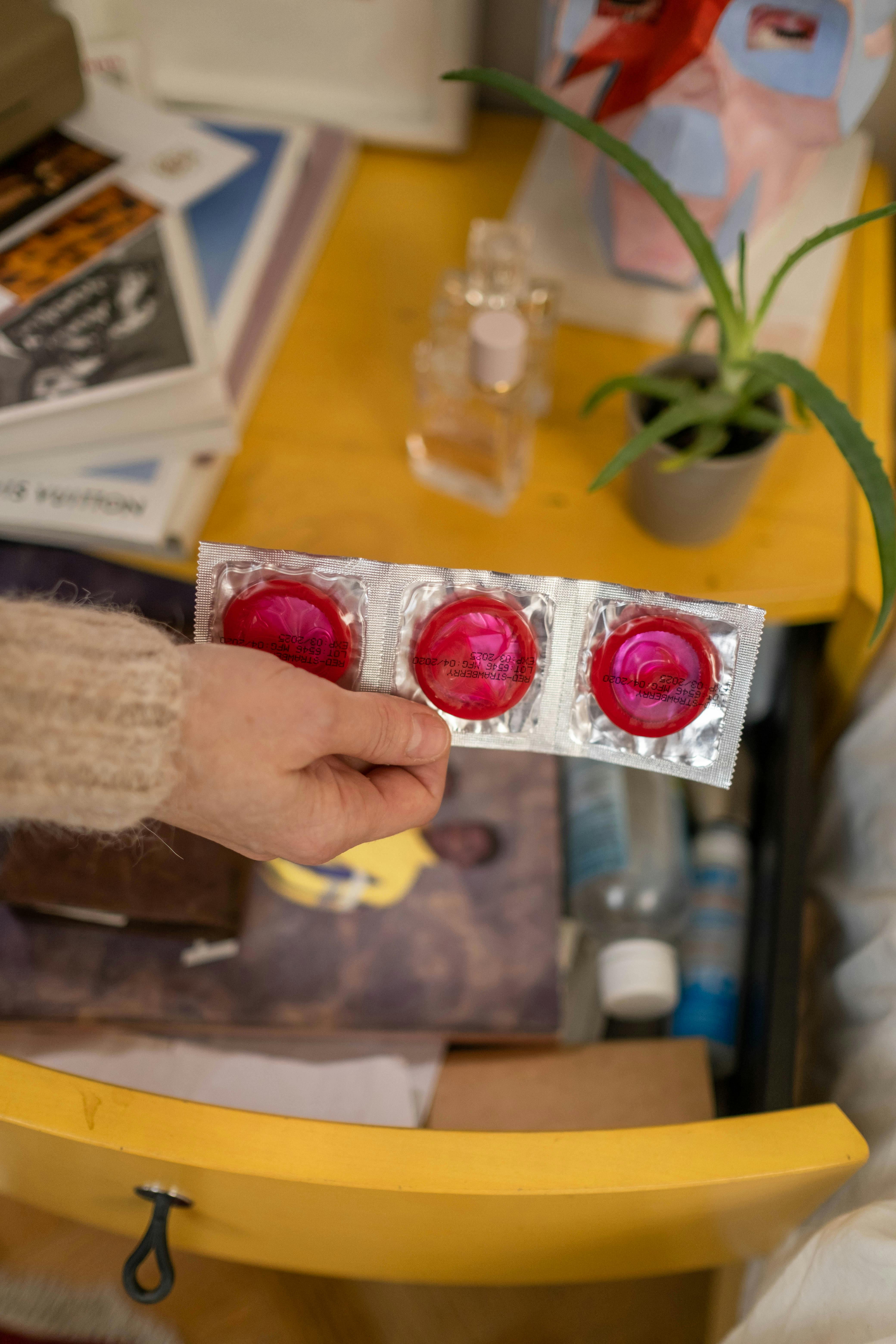 person holding three pink condoms