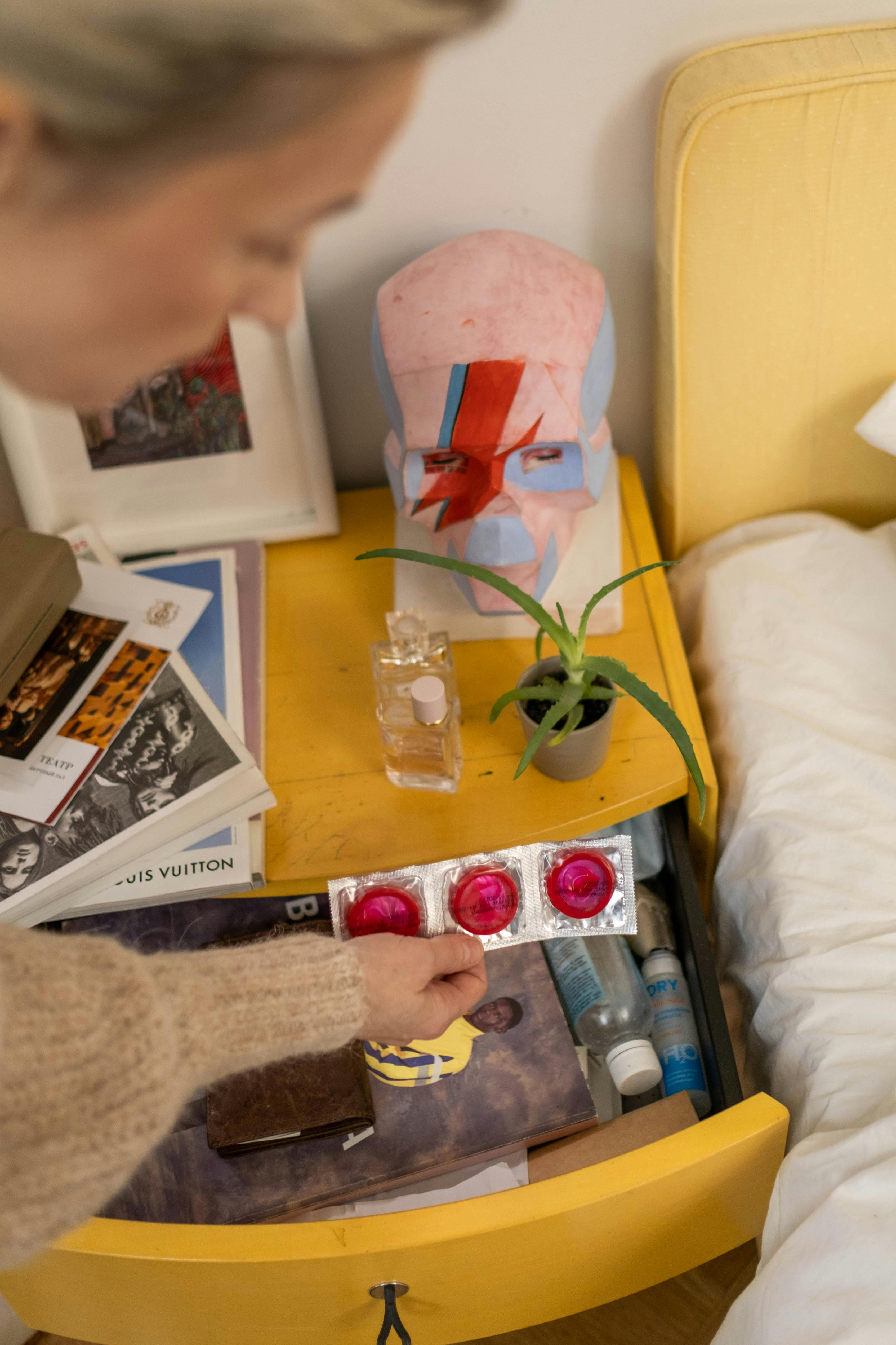 a person discovering three pink condoms from a bedside table