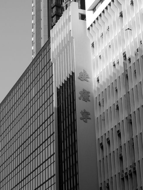 From below black and white of contemporary multistory building exterior with hieroglyphs on wall in daylight in city street under bright sky