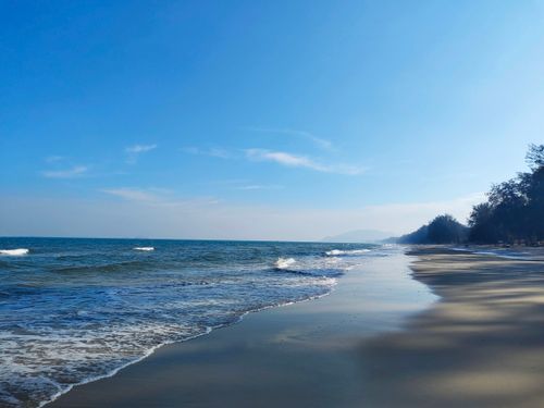 Free Tranquil beach scene at Hua Hin, Thailand with waves and clear blue sky. Stock Photo