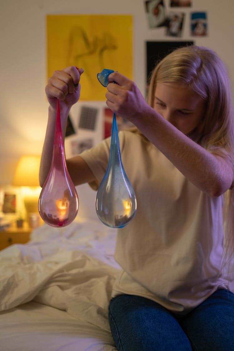 Person Holding Pink And Blue Balloons With Water