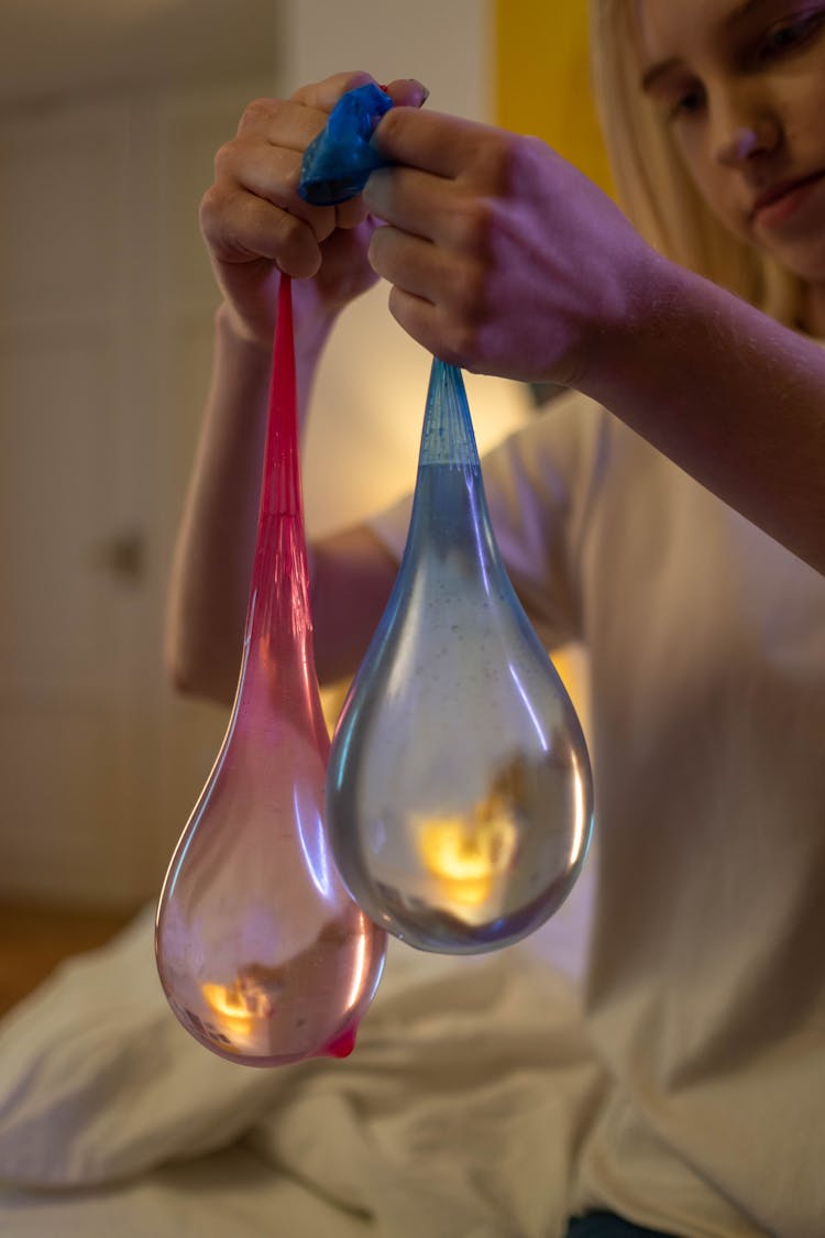 Hands Holding Pink And Blue Balloons With Water