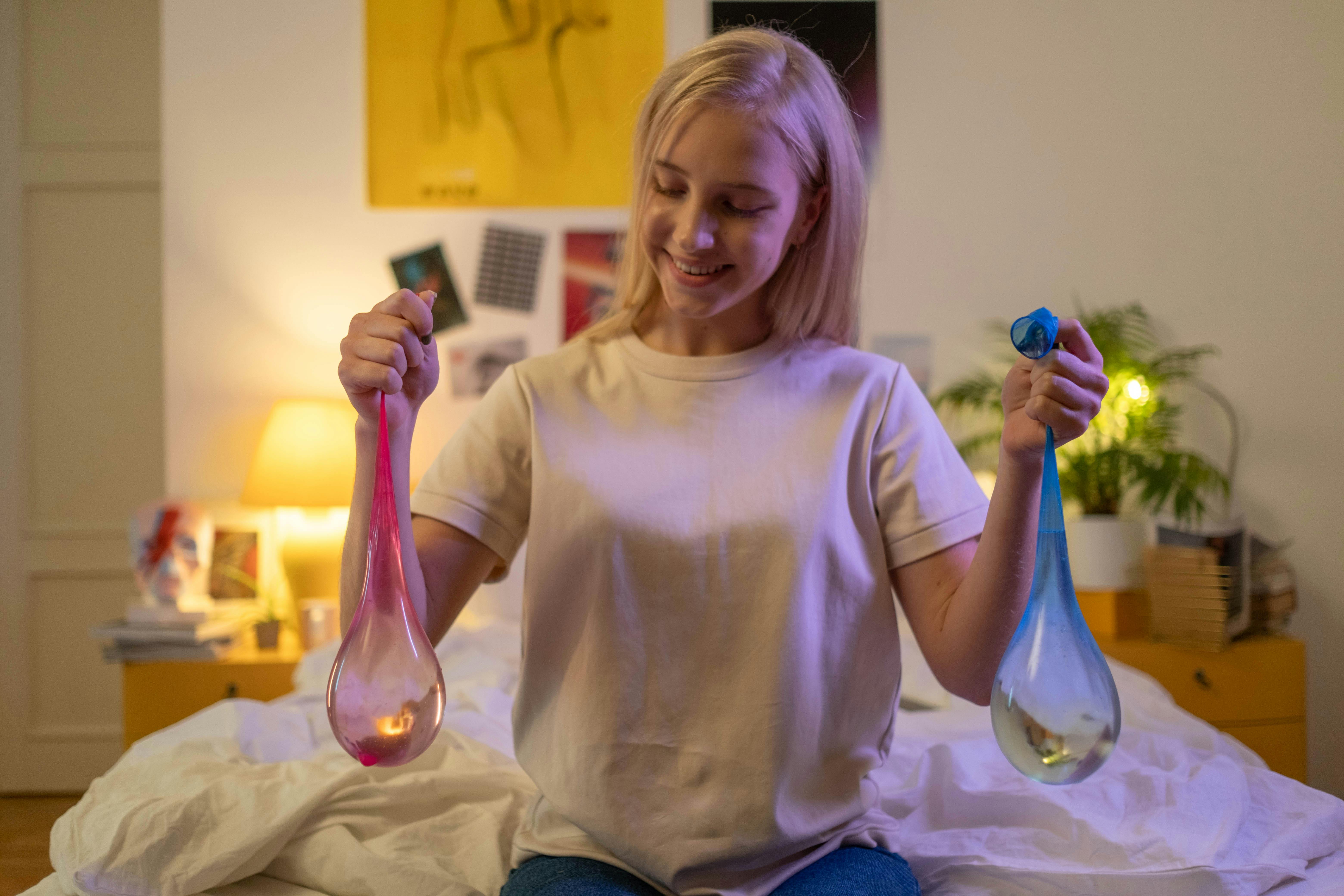 teenager holding two condoms with water