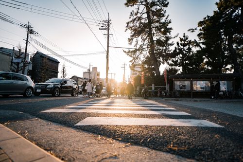 Free A busy pedestrian crossing in a sunlit city street with cars and people. Stock Photo