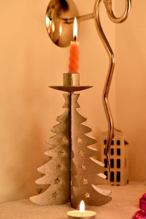 Free Elegant candle holder in Christmas tree shape casting warm festive glow. Stock Photo