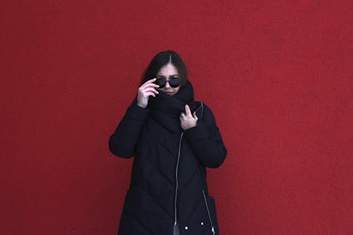 Free A Woman in Black Coat Standing Beside Red Wall Stock Photo