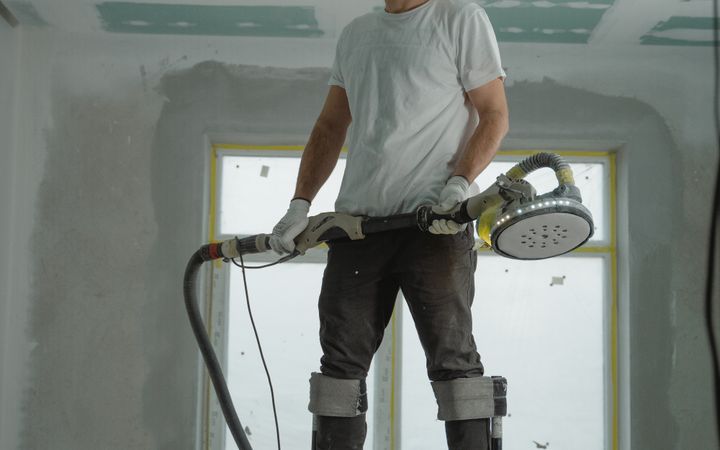 A construction worker using stilts for ceiling renovation indoors, enhancing space with expertise.