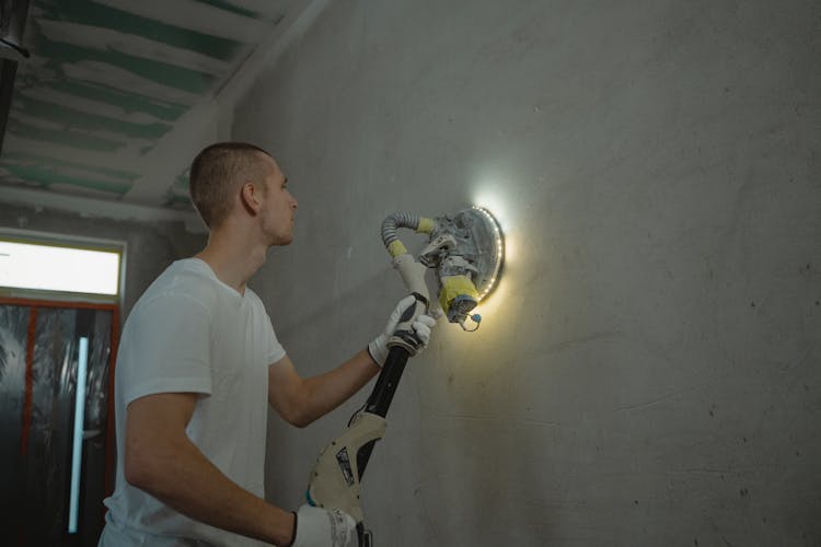 A Man Sanding The Wall