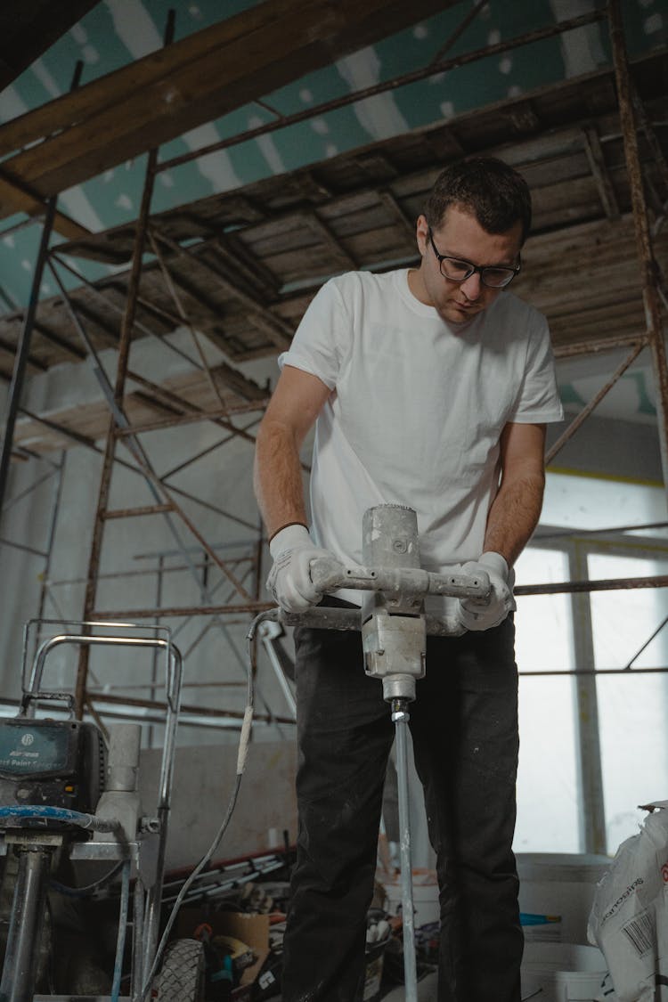 A Man In White Shirt Drilling 