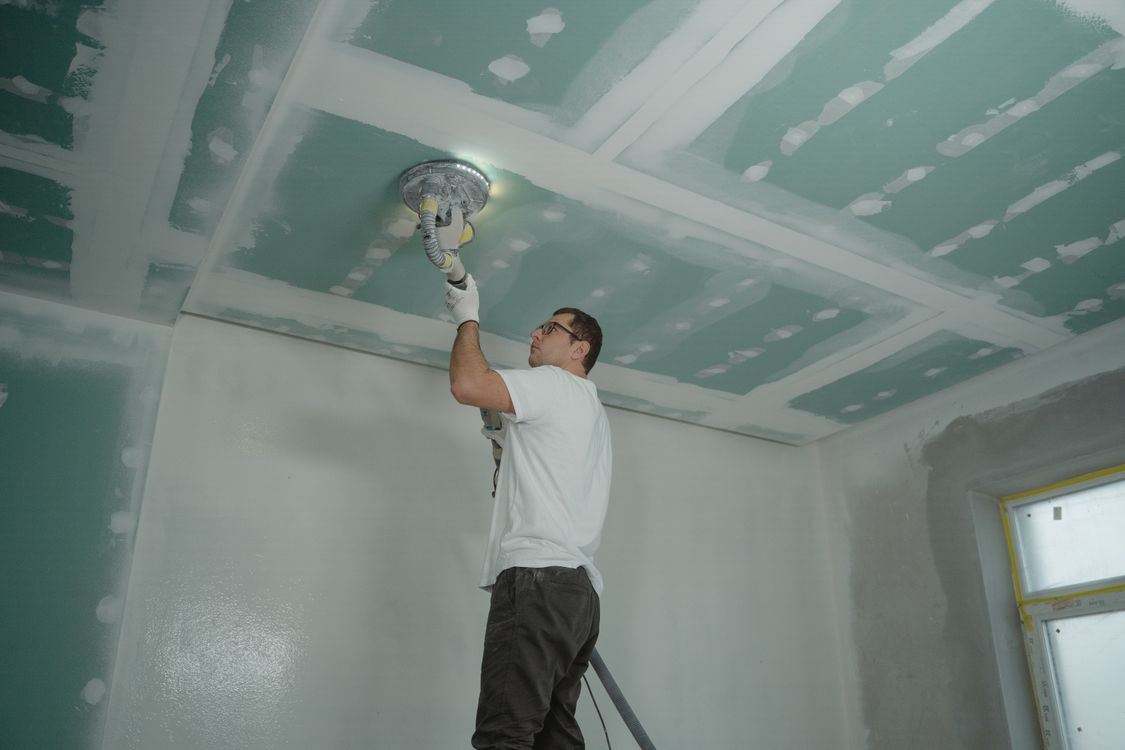 Worker smoothing a repaired ceiling during interior repairs
