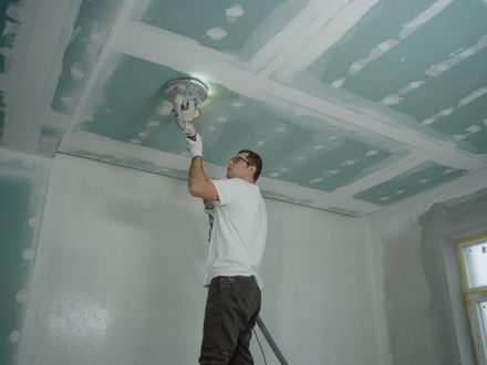 Popcorn ceiling being scraped off to a smooth finish