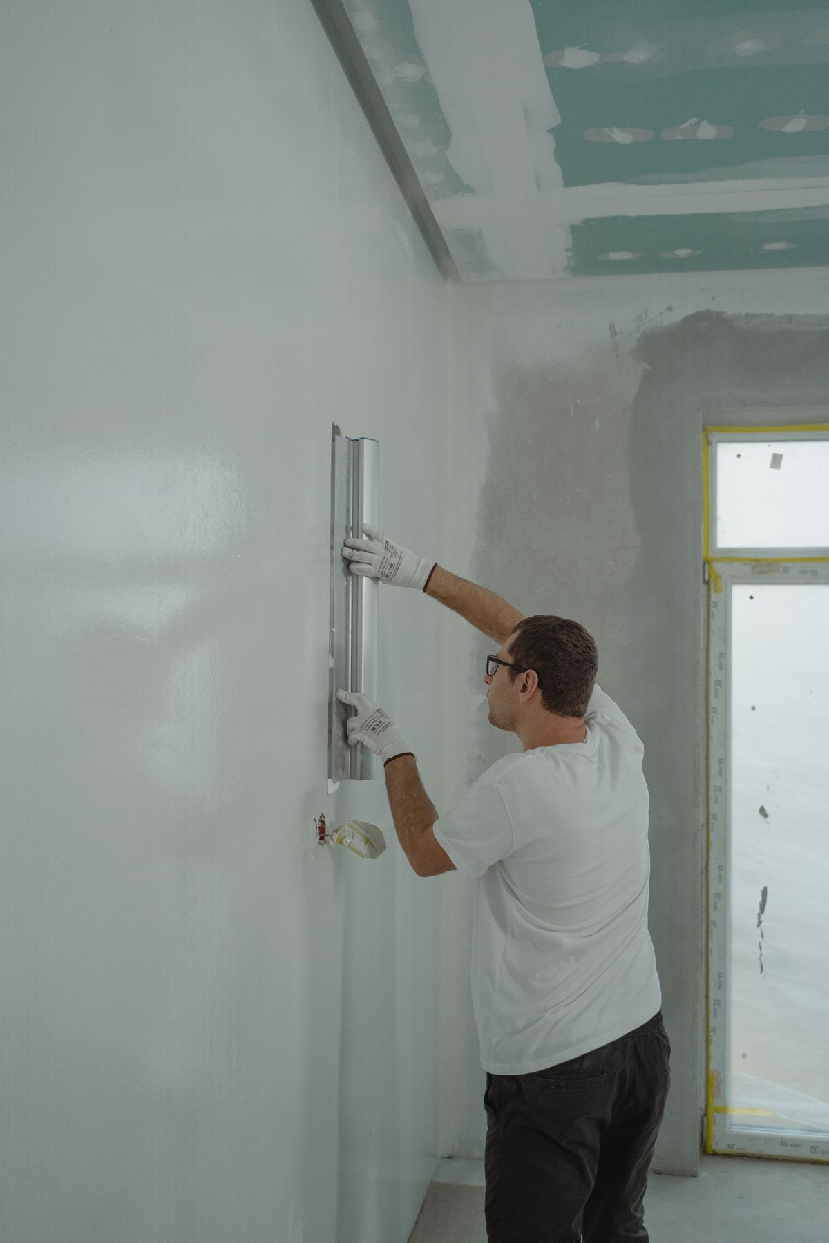 Painter finishing a wall surface with a skimming tool before priming