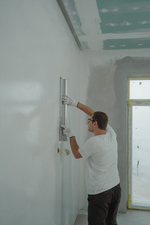 Free Adult male painting interior walls white in a house renovation project. Stock Photo
