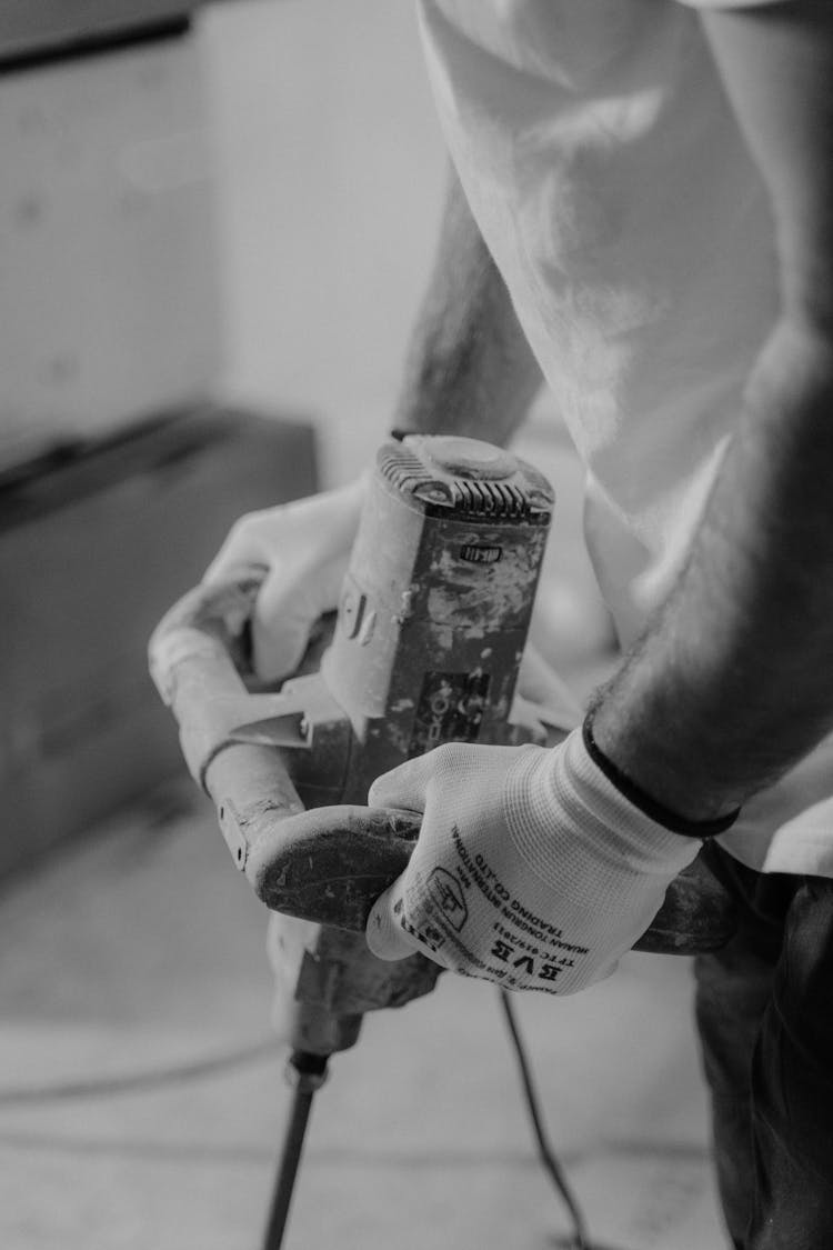 Grayscale Photo Of A Person Drilling