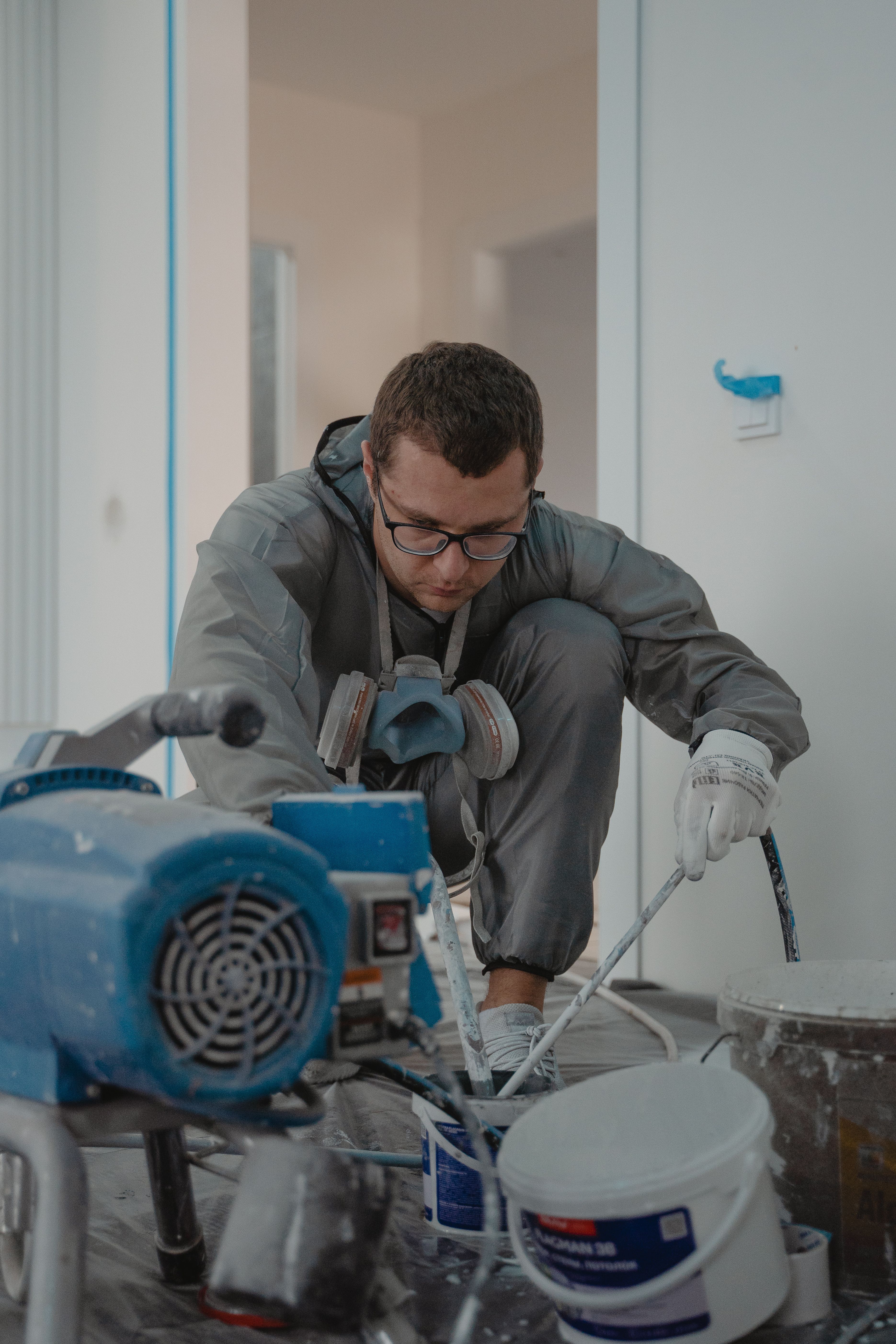 Man painting indoors for a home renovation pro ject using protective gear and paint sprayer