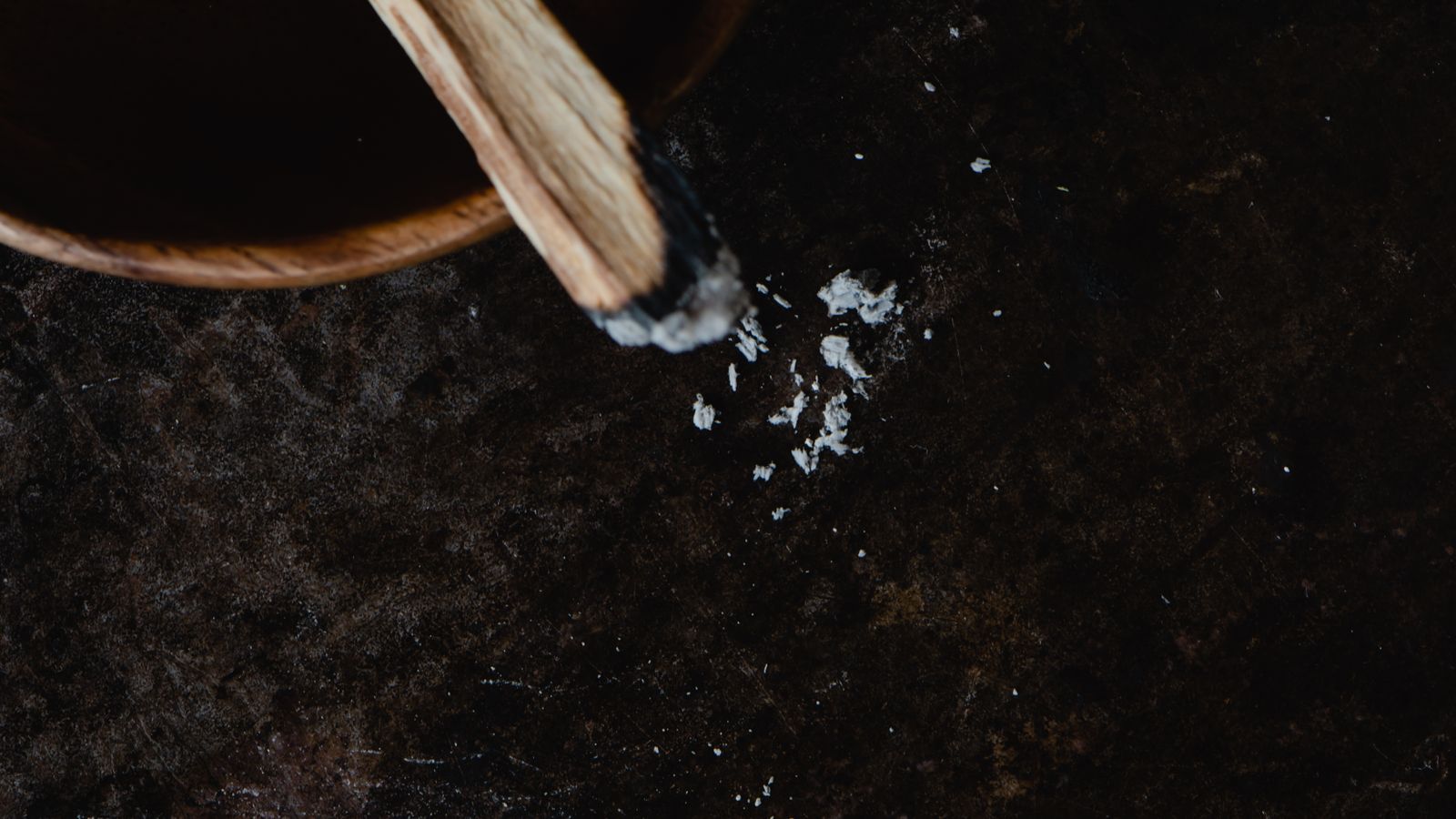 Burning palo santo stick in a wooden bowl during a spiritual clearing ritual