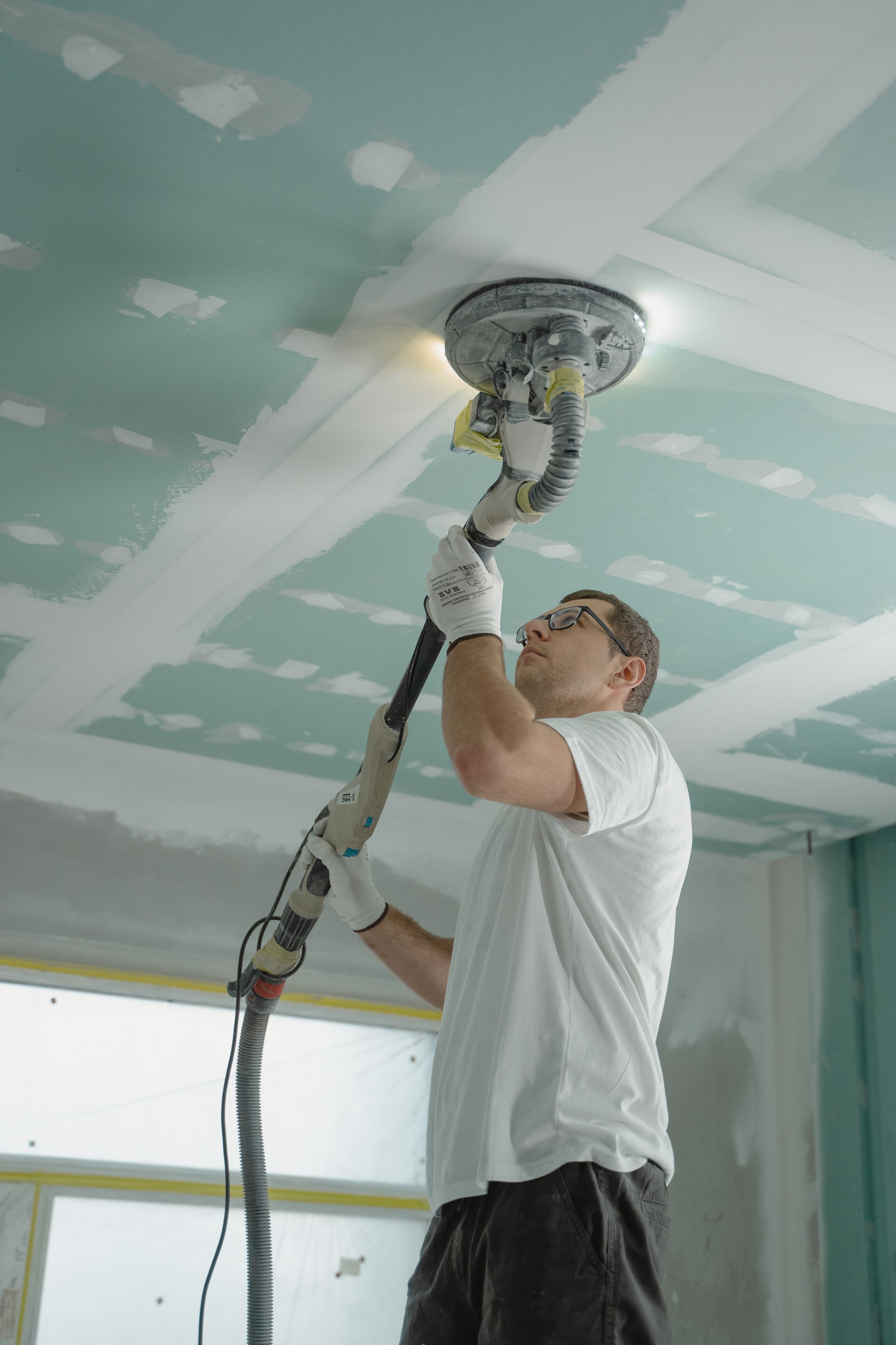 Personne en tenue de travail peignant un mur intérieur
