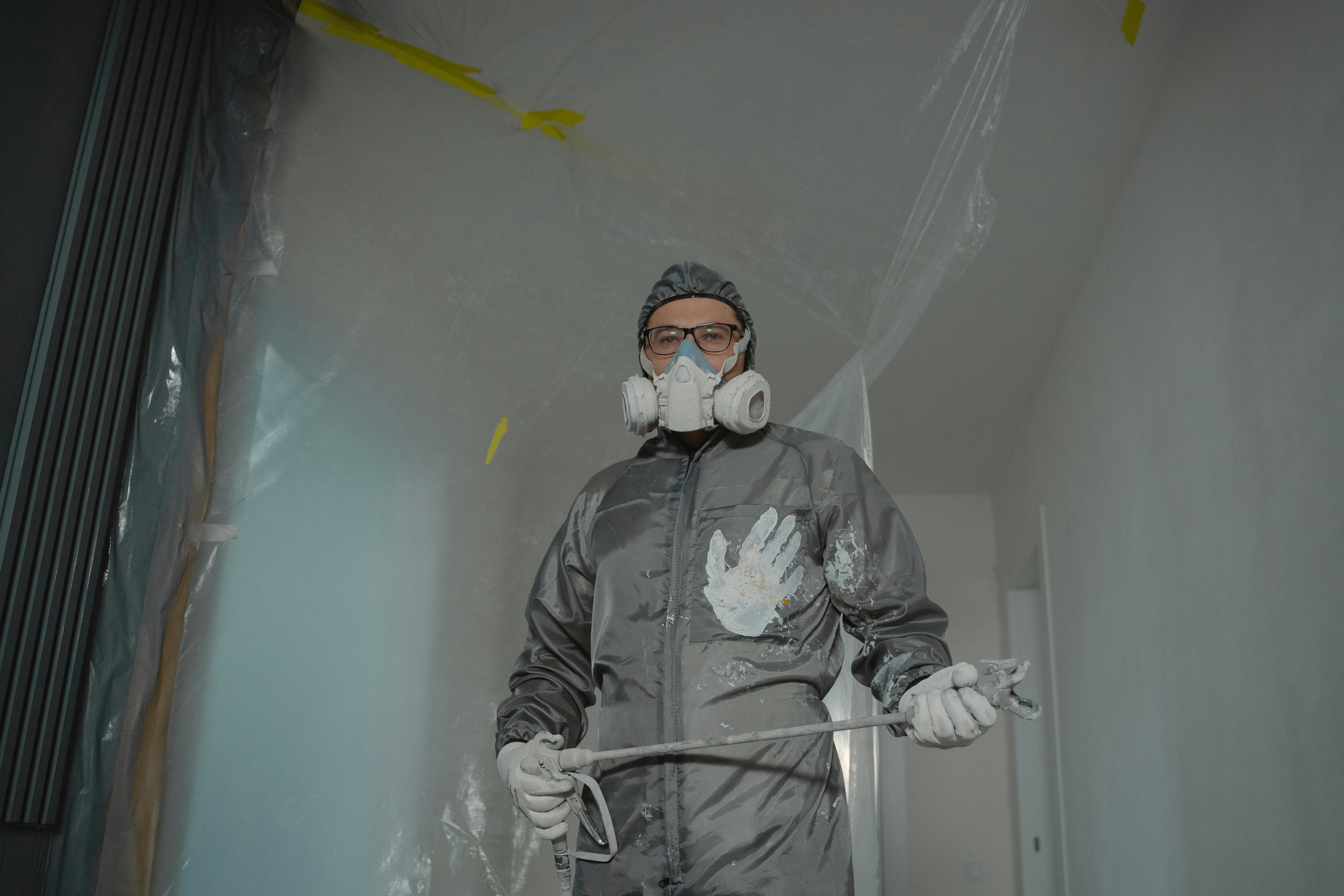 A Person in Gray Suit Painting a House