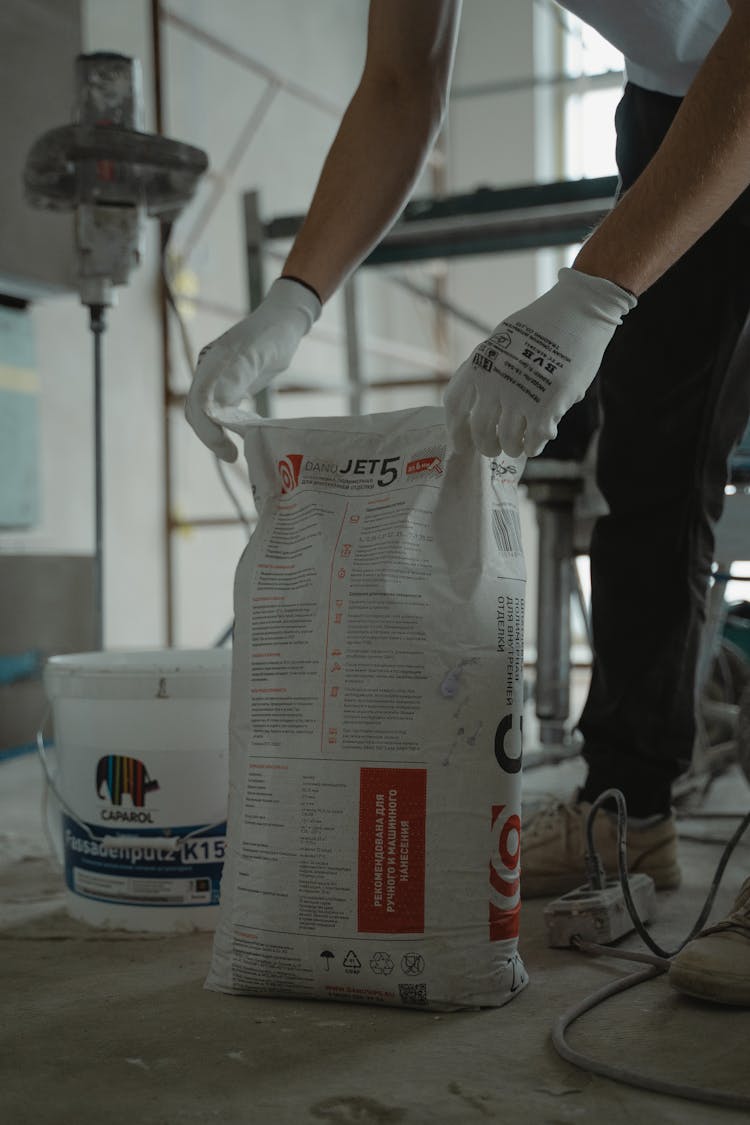 A Person Holding A Sack Of Cement