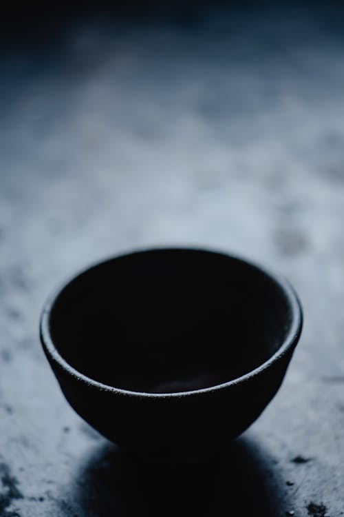 Черная круглая керамическая миска на серой поверхности