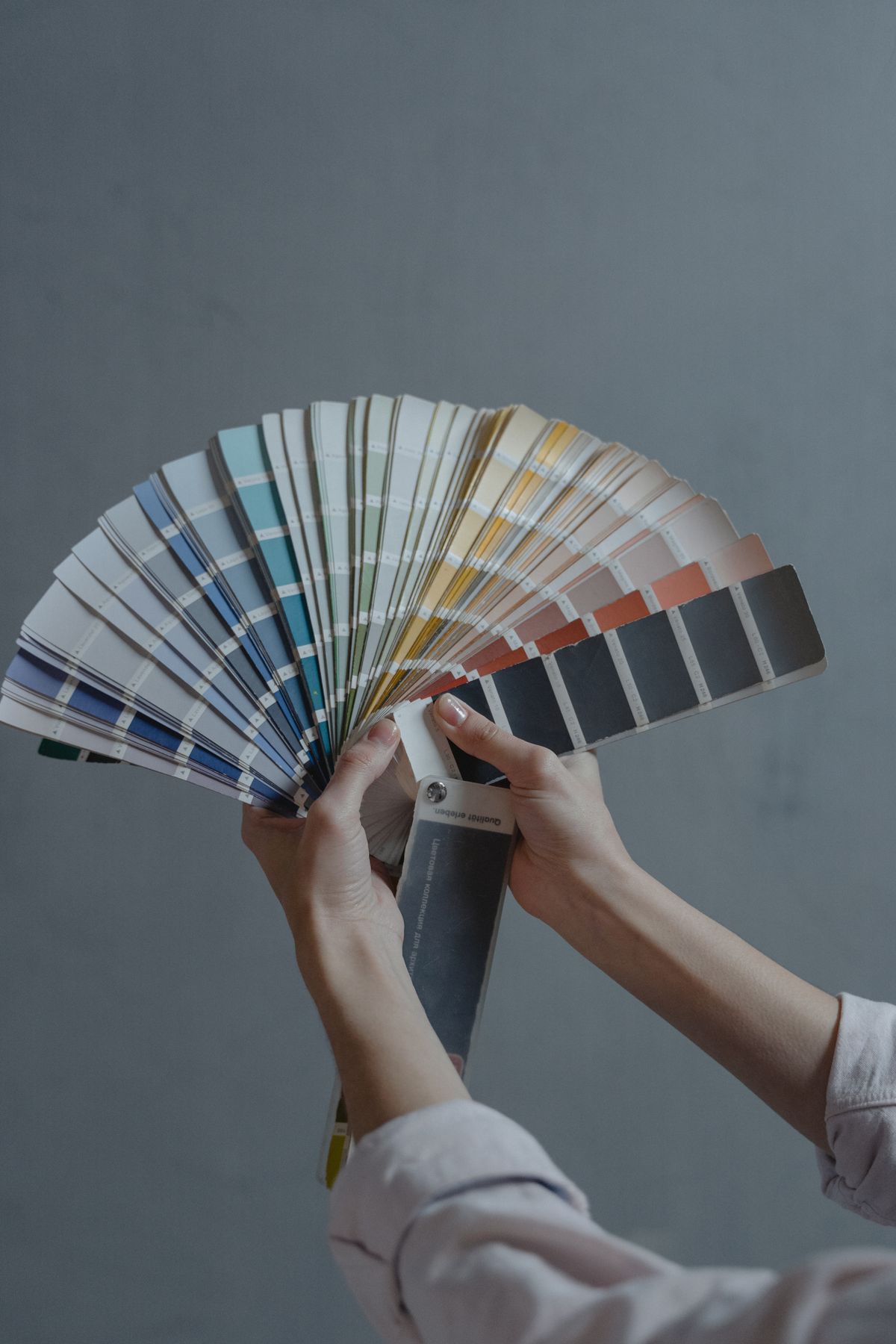 Hands holding a fanned-out selection of automotive paint colour swatches