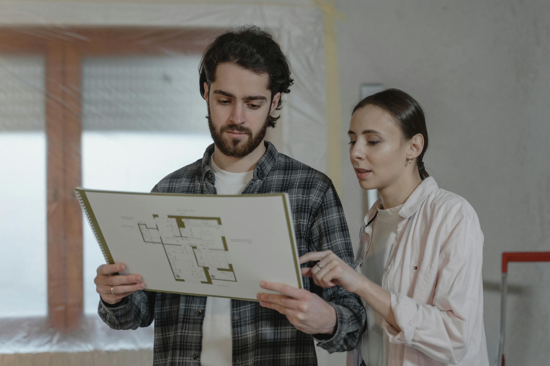 A man and woman examining a floor plan for home improvement indoors.