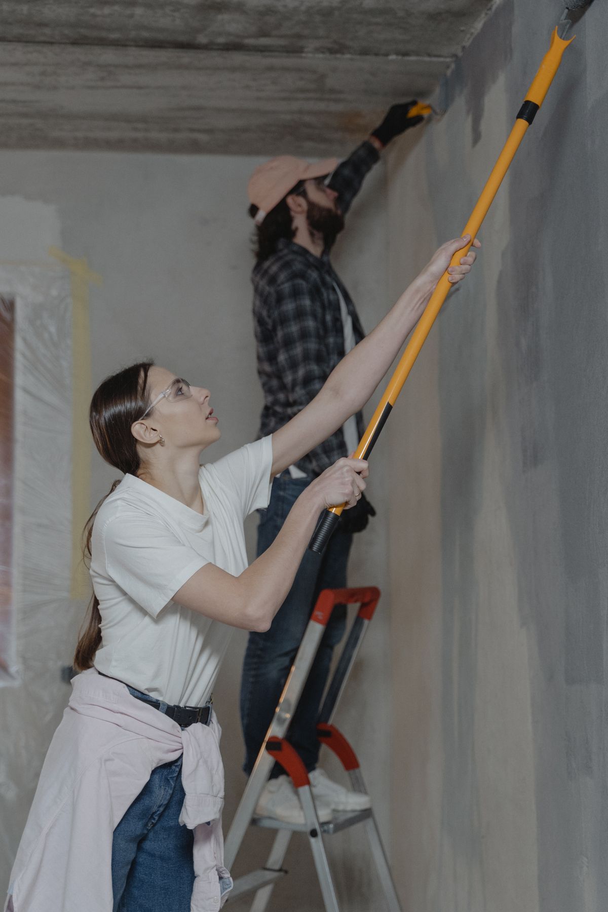 Casal reformando e pintando a parede de uma casa