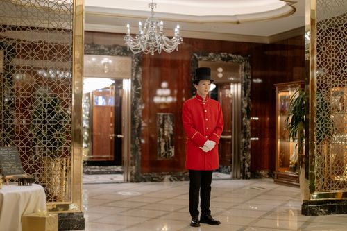 Free Elegant hotel lobby showcasing a uniformed doorman ready to welcome guests. Stock Photo