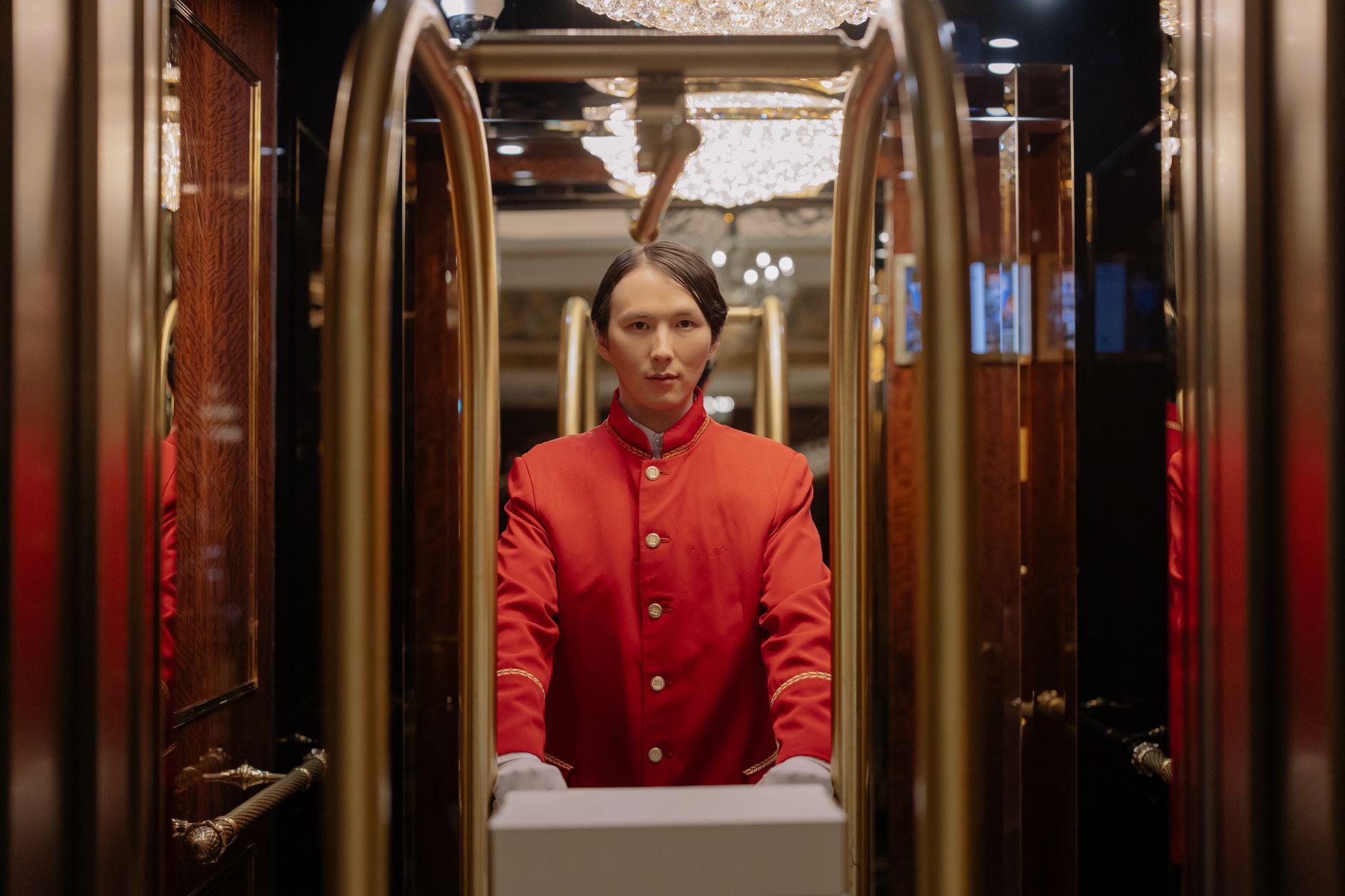 Bellboy in red uniform with luggage cart in luxurious hotel setting. Related image for Hotel Operations: What Comes Next for Modern Properties.