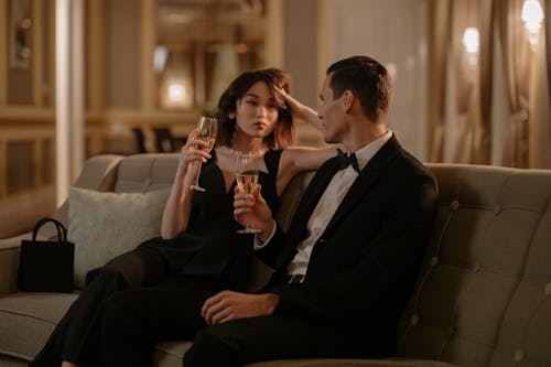 Man in Black Suit Jacket Sitting Beside Woman in Black Dress