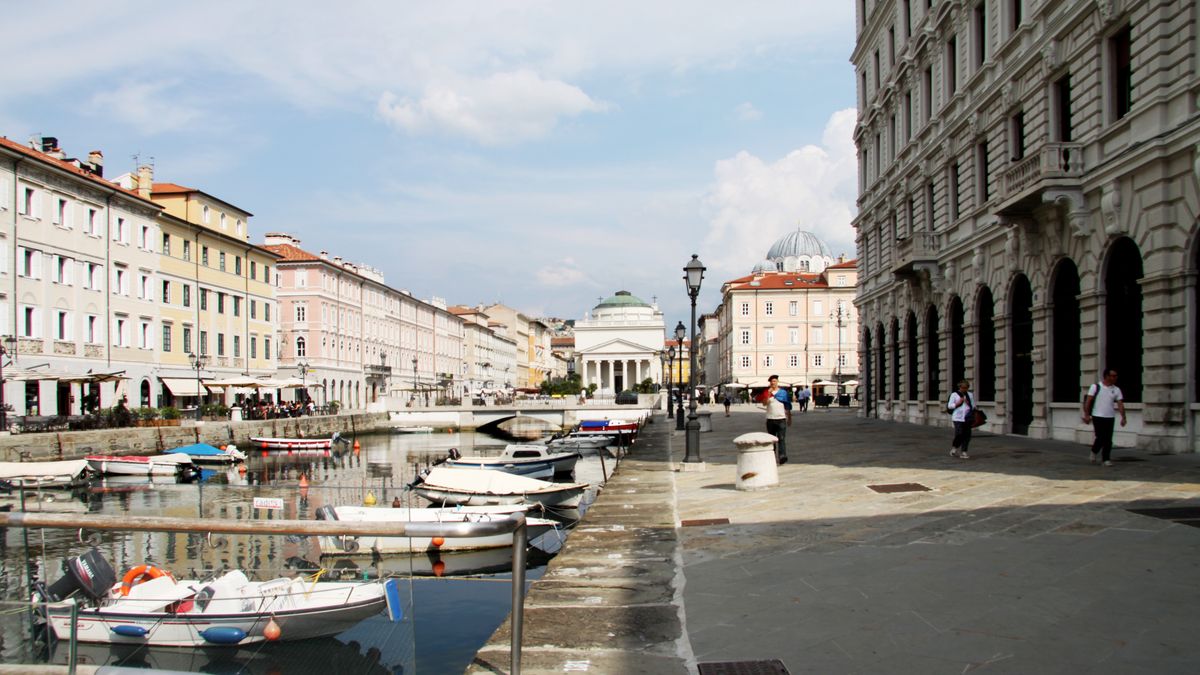 Boats on a canal in Trieste flanked by classic urban architecture
