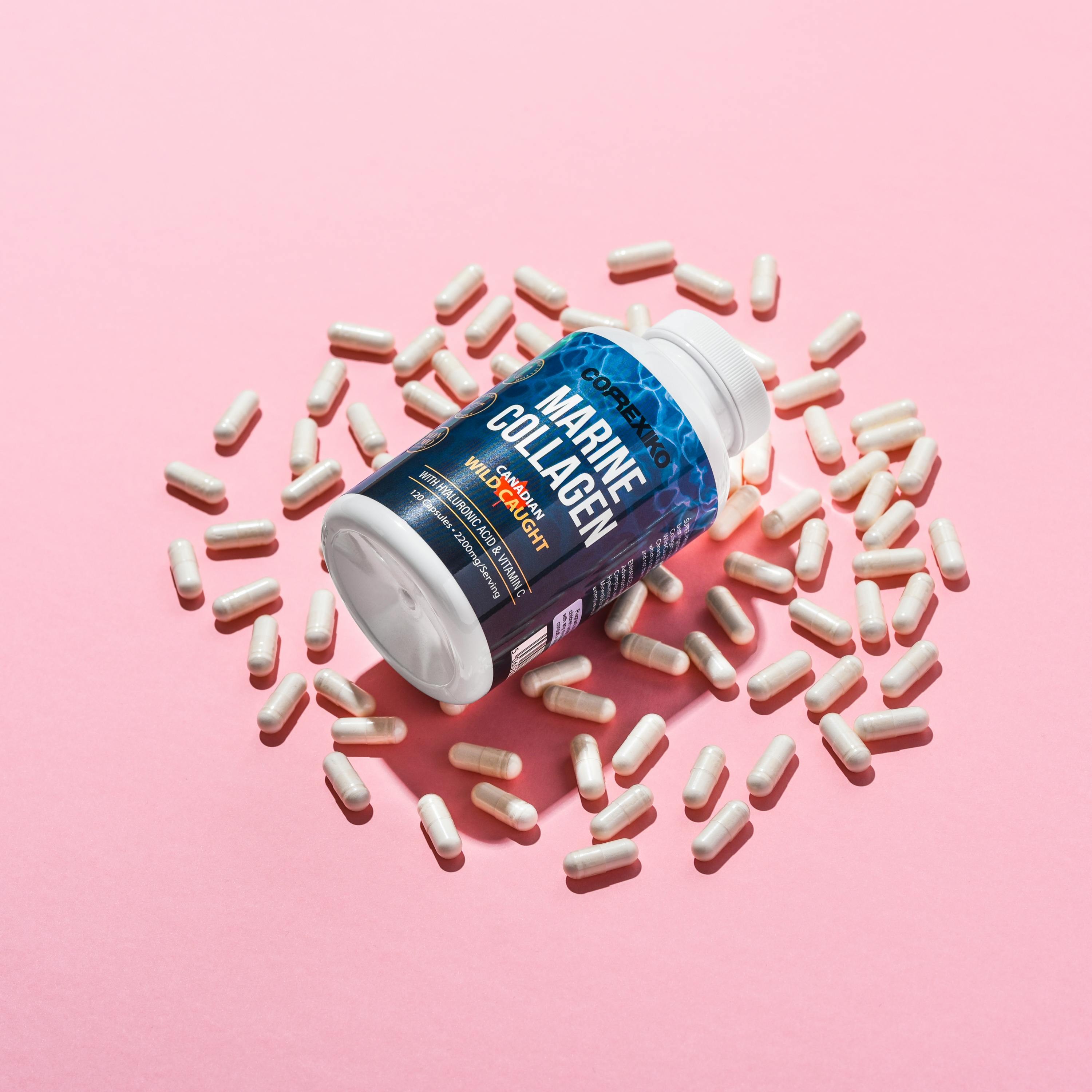 Image of marine collagen supplement capsules scattered on a pink surface.