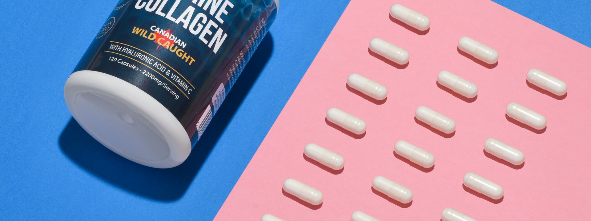 Clean supplement product scene with capsules on a bright blue and pink surface