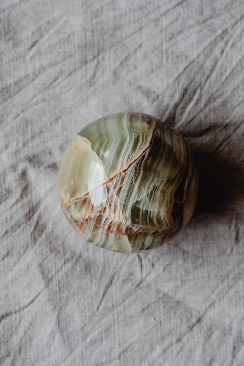 A Green and White Round Gemstone on Gray Textile