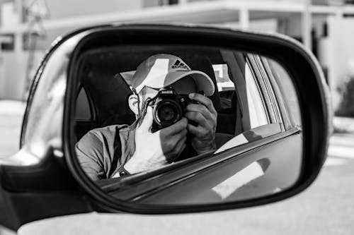Monochrome Shot of a Man Taking a Picture Using a DSLR Camera