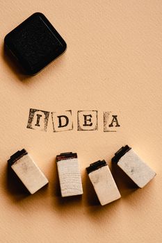 Close-up of letter stamps spelling 'idea' with ink pad on an orange background.