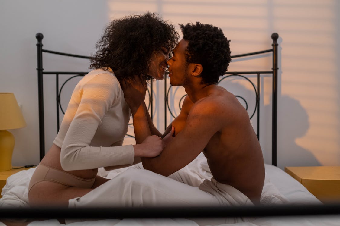 Free Couple Sitting on Bed and Kissing Stock Photo