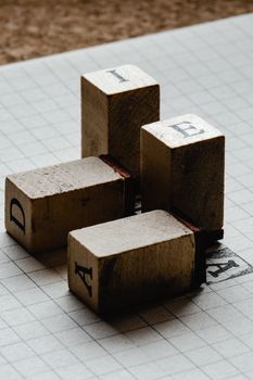 Rustic wooden stamps on graph paper with letters A, D, I, and E, creating a nostalgic feel.