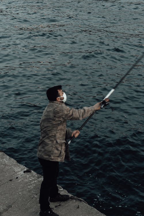 Free Anonymous fisherman catching fish with rod in river Stock Photo