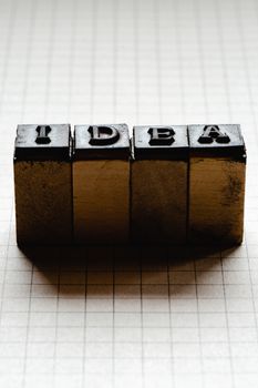 Vintage blocks spelling 'idea' on grid paper, evoking creativity and inspiration.