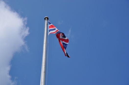 Union Jack flag waving on a flagpole against a clear blue sky in London, UK.