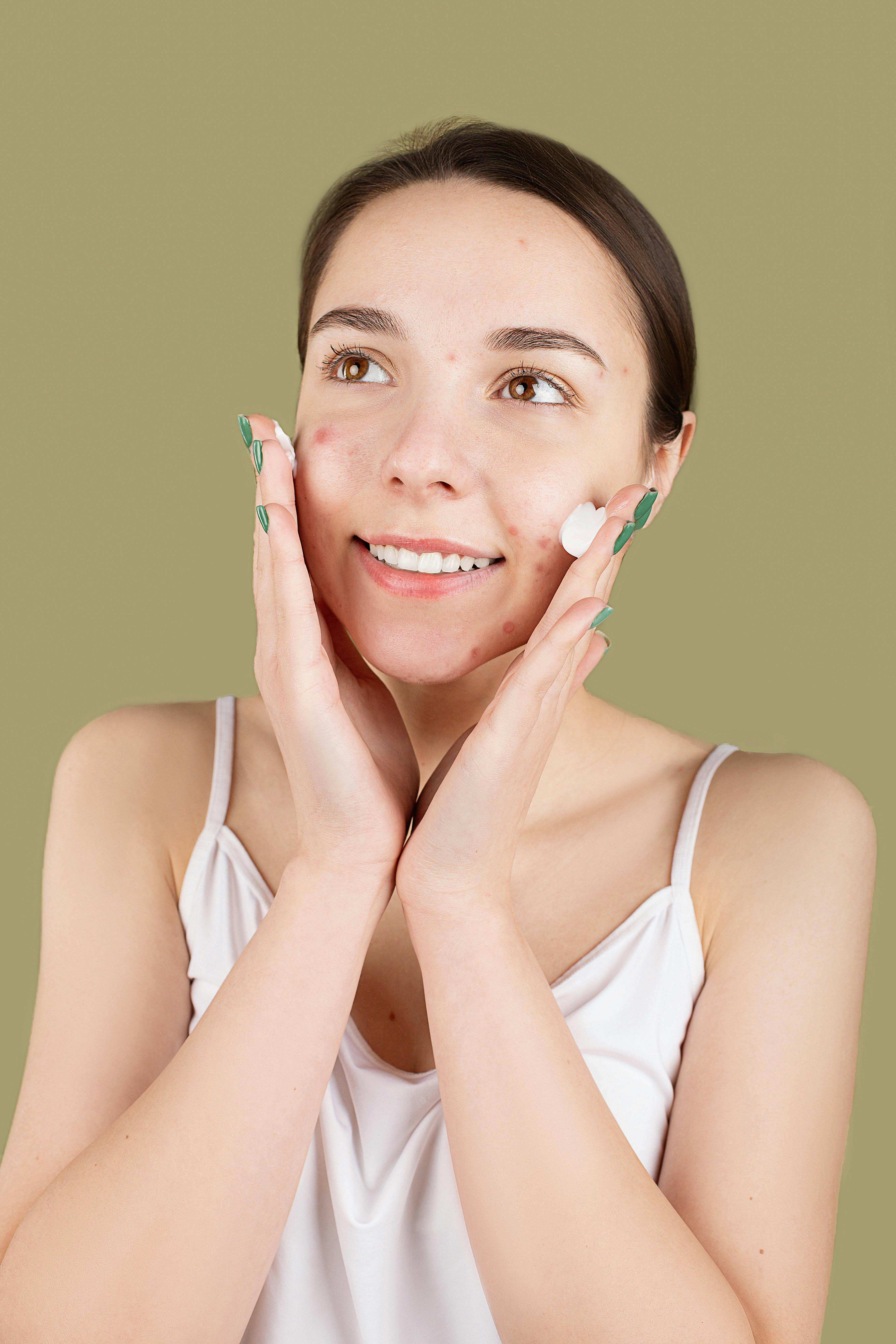 smiling teenager applying a facial cream on her face