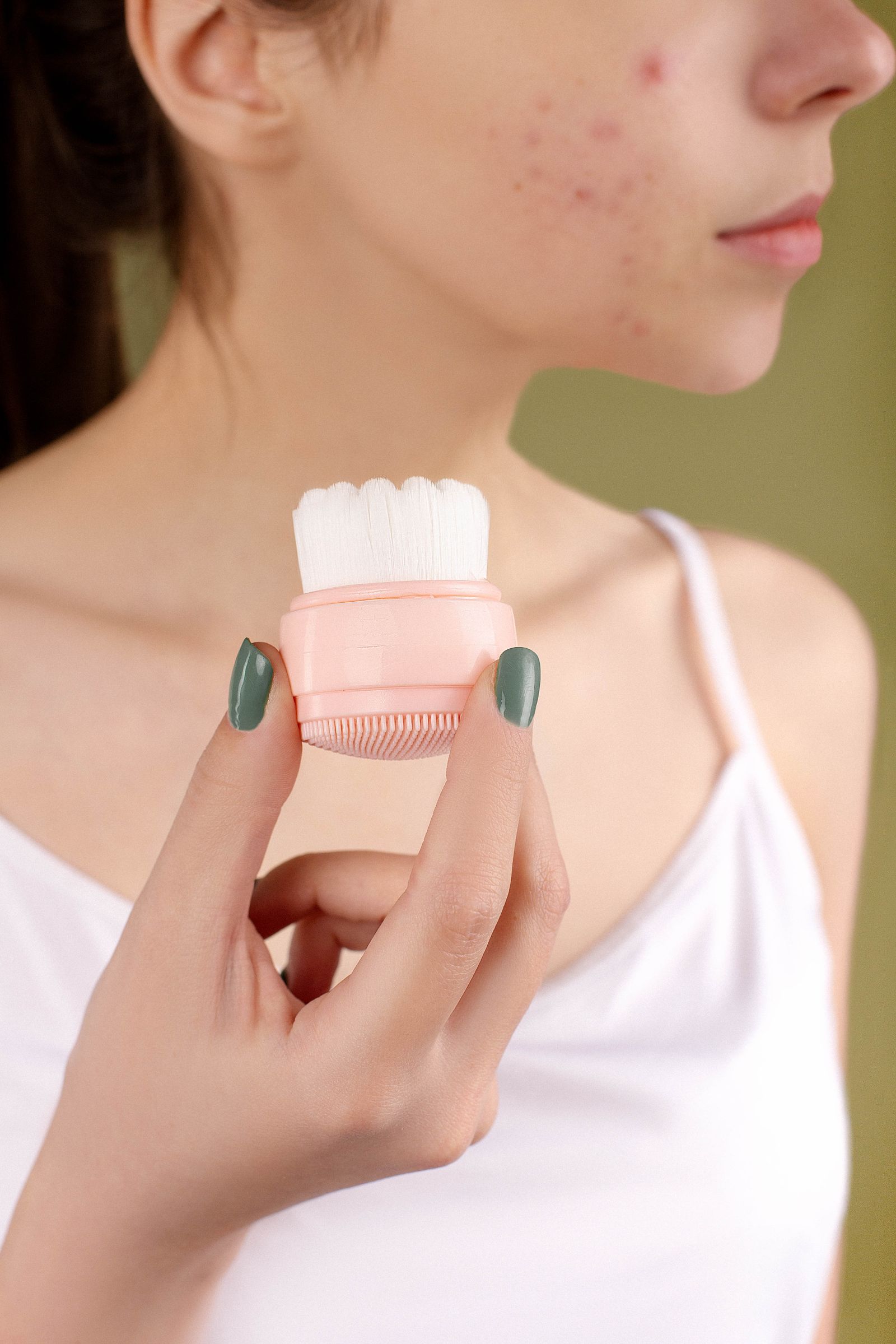 Woman holding a facial cleansing brush during a personal beauty care routine