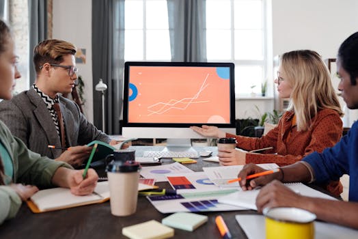 A diverse team discusses data visualization on a computer screen in an office setting.