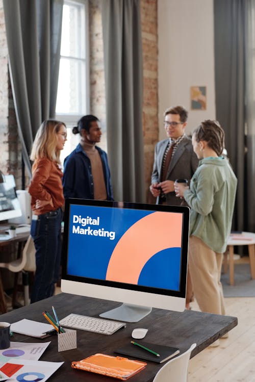 A Group of People Standing Near a Computer on the Table