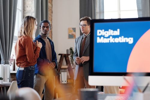 Free Group of colleagues discussing digital marketing strategies in an office setting. Stock Photo