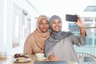 Woman in Brown Hijab Holding Black Smartphone